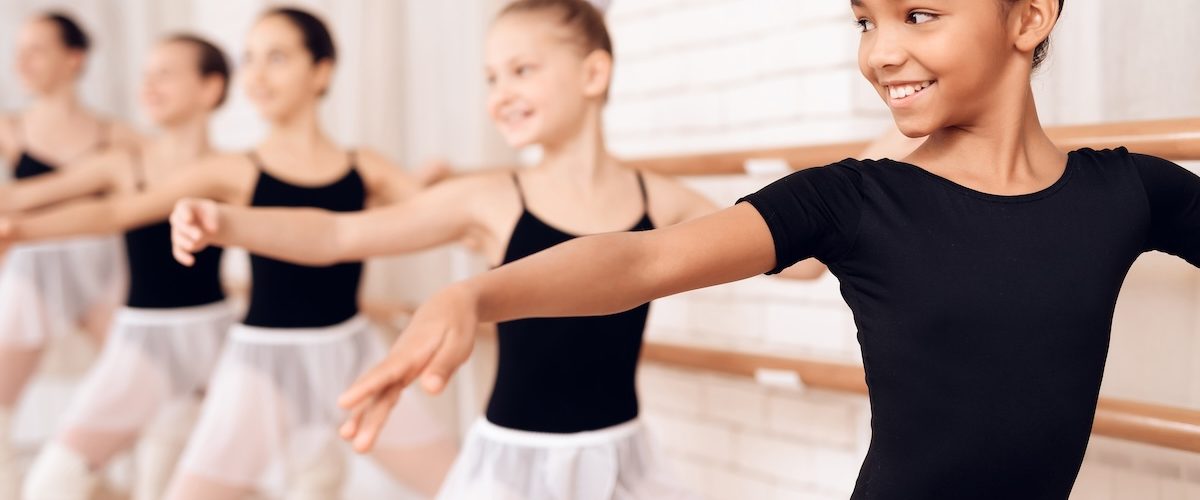 Young ballerinas rehearsing in the ballet class. Young ballerinas rehearsing in the ballet class. They perform different choreographic exercises. They stand in different positions near the ballet barr.