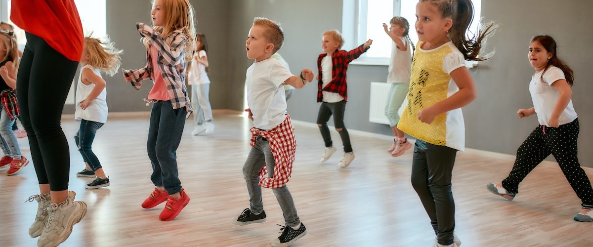 Full of energy. Group of little boys and girls dancing while having choreography class in the dance studio. Female dance teacher and children Group of little boys and girls dancing while having choreography class in the dance studio. Female dance teacher and children. Contemp dance. Hip hop. Kids and sport. Full length
